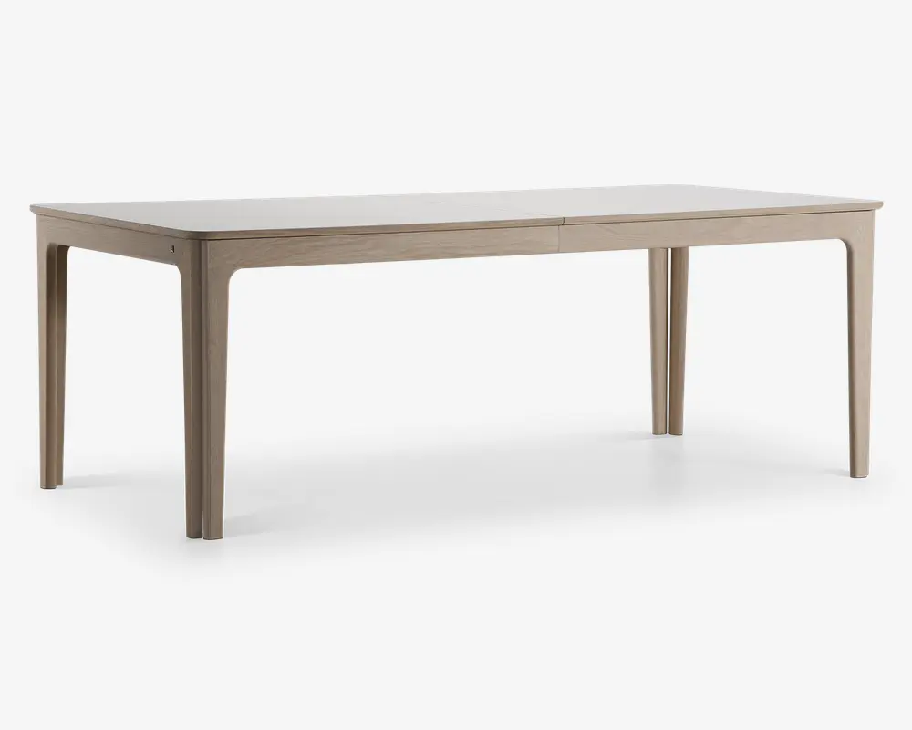 Rektangulært bord med en glat, lys bordplade og matchende ben. Bordet har et minimalistisk design med let afrundede hjørner og kanter, og benene er lige med diskrete indadgående kurver øverst. Overfladen har en mat finish, hvilket giver et moderne og rent udtryk.