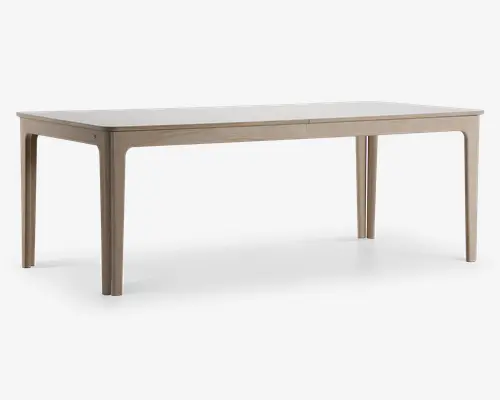 Rektangulært bord med en glat, lys bordplade og matchende ben. Bordet har et minimalistisk design med let afrundede hjørner og kanter, og benene er lige med diskrete indadgående kurver øverst. Overfladen har en mat finish, hvilket giver et moderne og rent udtryk.