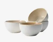 Sæt med fire keramikskåle med en glat, mat hvid yderside og en blank, lysebeige inderside. Hver skål har en rund form med en let tyk kant, hvilket giver et moderne og minimalistisk udtryk. Skålene virker robuste og egner sig til servering af suppe, morgenmad eller salater.