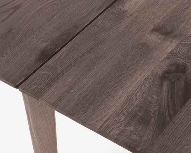 Nærbillede af en bordplade med rustik, naturlig træstruktur. Overfladen har synlige knaster og teksturerede årer, hvilket giver et autentisk, håndlavet udtryk. Træet er mellembrunt med diskrete farvevariationer, og bordet har en solid, plankeagtig konstruktion.