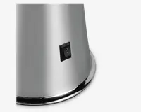 Nærbillede af en overflade i børstet rustfrit stål med en sort vippekontakt. Kontakten er rektangulær og har tydelige 'I' (tændt) og 'O' (slukket) markeringer. Basen har en let udvidet, afrundet kant, hvilket giver et solidt udtryk.