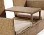Nærbillede af et udendørs møbel i flet med indbygget, hævet sidebord. Bordet er rektangulært med en ramme i samme flet og en flad overflade med trælook. Siddeområdet har tykke, lyse beige hynder for ekstra komfort. Designet er moderne og funktionelt, hvor bordet er praktisk placeret mellem to siddepladser.