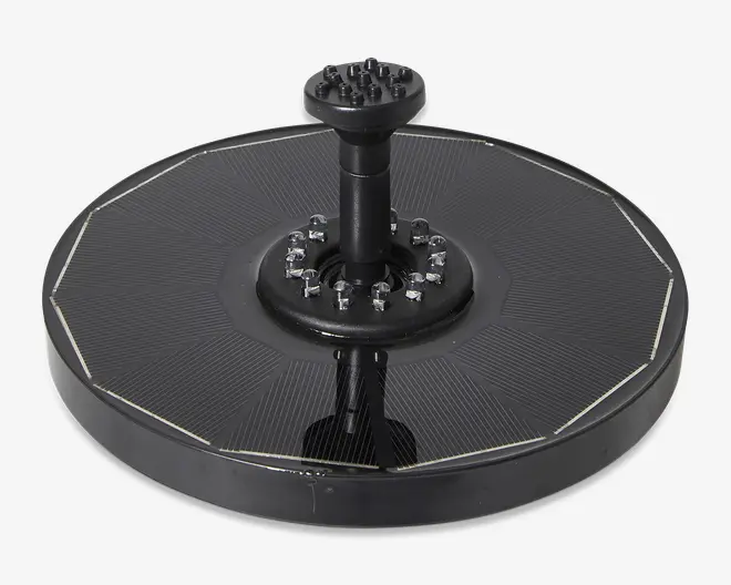 Rund, sort enhed med en flad, segmenteret overflade bestående af solcellepaneler. I midten er der en hævet cylindrisk sektion med flere små dyser arrangeret i en cirkel samt en højere dyse i midten, sandsynligvis til vandstråle. Kanten er glat og let hævet, hvilket giver produktet et robust udseende.