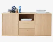 Opbevaringsmøbel i lyst egetræslook med to store låger i hver side, to centrale skuffer med små runde metalgreb og en åben hylde over skufferne. Toppen er dekoreret med stakke af bøger samt forskellige dekorative vaser og skåle. Designet er moderne og minimalistisk med rene linjer og en glat træstruktur.