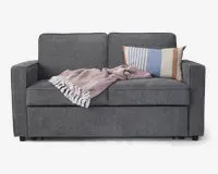 En moderne to-personers sofa betrukket med mørkegråt stof, med rene, lige linjer og firkantede armlæn. Sædehynderne er faste, og ryghynderne er lidt højere for ekstra støtte. På højre side ligger en rektangulær pude med vandrette striber i blå, beige og brun. Over sædet er der lagt et lyserødt, tekstureret tæppe med hvide frynser.