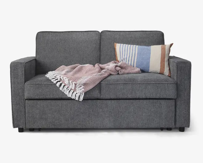 En moderne to-personers sofa betrukket med mørkegråt stof, med rene, lige linjer og firkantede armlæn. Sædehynderne er faste, og ryghynderne er lidt højere for ekstra støtte. På højre side ligger en rektangulær pude med vandrette striber i blå, beige og brun. Over sædet er der lagt et lyserødt, tekstureret tæppe med hvide frynser.