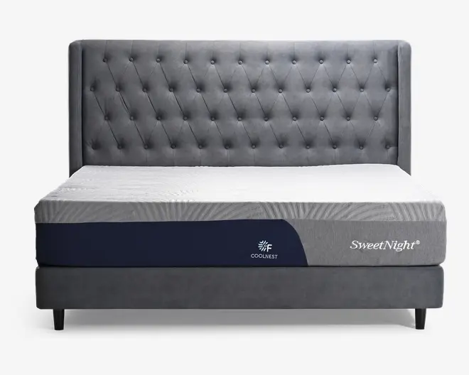 En moderne seng med en høj, polstret sengegavl i mørkegråt stof med knapdetaljer. Madrassen har et tofarvet design med en lysegrå top og mørkeblå sider. På siden af madrassen står der 'COOLNEST' og 'SweetNight', hvilket indikerer køleteknologi og mærke. Sengerammen er også betrukket med matchende mørkegråt stof, og det samlede design er stilrent og moderne.