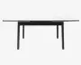 Rektangulært bord med et slankt, moderne design med hvid bordplade og sorte ben. Bordet har udtræksplader i begge ender, så det kan udvides til flere siddepladser. Benene er lige og stabile, hvilket giver god støtte. Udtrykket er minimalistisk og nutidigt.