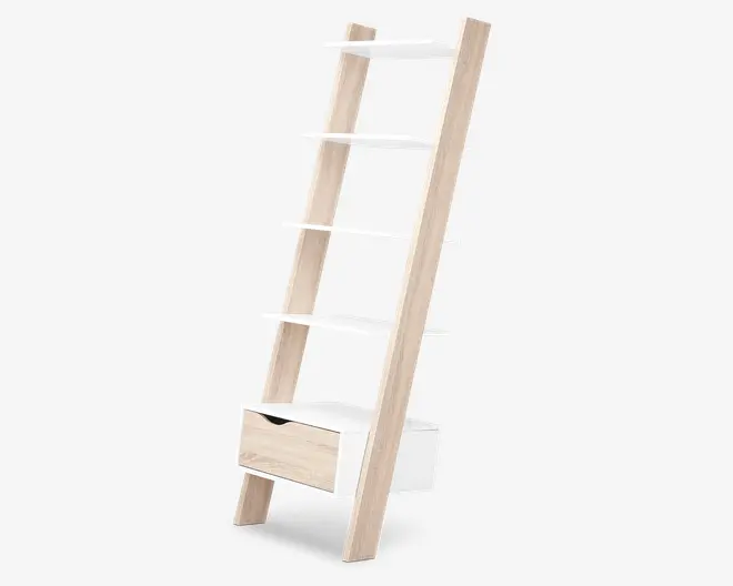 En moderne reol i stige-design med en ramme i lyst træ og fem hvide hylder i forskellige dybder. Nederst er der en enkelt skuffe med udskåret greb, som kombinerer hvide og lyse træoverflader. Reolen læner sig op ad væggen og har et moderne, pladsbesparende udtryk.