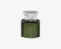 En lille, cylindrisk beholder lavet af mørkegrønt glas med lodrette rillede detaljer. Den har et bredt, klart glaslåg med facetslebet, udvidet design, der giver et dekorativt udtryk. Det samlede udseende er elegant og moderne, velegnet til udstilling.