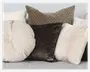 En samling dekorative puder i forskellige former, størrelser og teksturer. Arrangementet inkluderer en rund, cremefarvet pude med syede radiære linjer, en firkantet pude med mørkebrun blomsterstruktur, en stor firkantet pude med geometrisk beige og brunt mønster samt to firkantede puder i bløde, lyse beige og offwhite stoffer. Pudernes materialer varierer mellem velour, tekstur og mønster, hvilket skaber et hyggeligt og stilfuldt udtryk.