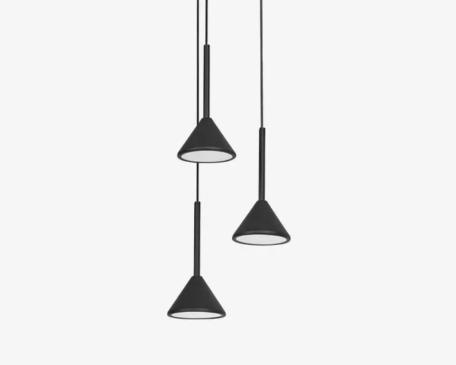 Tre pendellamper med mat sorte, kegleformede skærme, hver ophængt i en sort ledning i forskellige højder. Lampeskærmenes inderside er hvid, hvilket giver en ren kontrast og forbedrer lysrefleksionen. Designet er moderne og minimalistisk, velegnet til nutidige indretninger.
