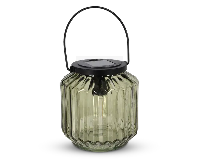 Lanterne af klart glas med lodret rillet struktur, sort metal låg med indbygget solcellepanel og buet metalhank til ophængning. Lanternen har en bred åbning og en solid bund, velegnet til udendørs eller indendørs brug.