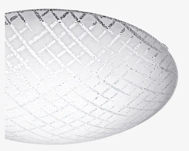 Et nærbillede af en kuppelformet glasplade med frostet overflade og et geometrisk krydsmønster indgraveret. Glasset har en tekstureret finish, som giver et blødt og diffust lys. Mønsteret består af krydsende linjer, der danner diamantformer over hele kuplen.