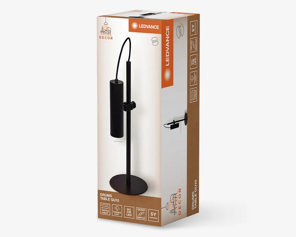 Emballagen viser en moderne bordlampe med en cylindrisk, lodret rillet sort lampeskærm, der hænger fra en buet arm, som er fastgjort til en slank, lige stander og en rund fod. Lampen har et minimalistisk design, der passer til moderne indretning, og er kompatibel med GU10 LED-pærer. Æsken fremhæver funktioner som 5 års garanti, tænd/sluk-knap og maksimal 5W LED-brug.