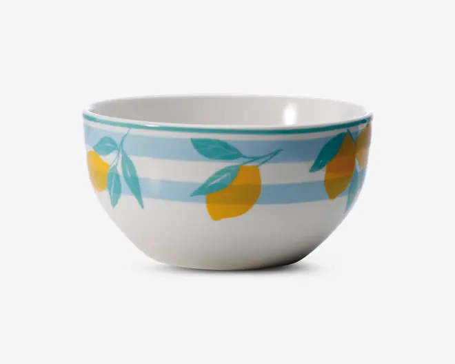 Rund keramikskål med blank overflade, dekoreret med et mønster af gule citroner med grønne blade på en baggrund af lyseblå og hvide vandrette striber. Skålens kant har en tynd turkis linje. Indersiden er ensfarvet hvid.