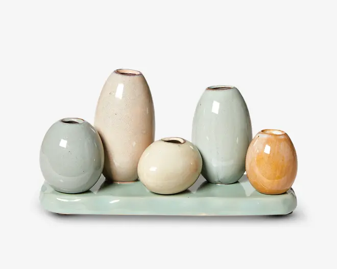 Sæt med fem små, runde keramikvaser i pastelfarver, herunder lyseblå, creme, beige og lyseorange, arrangeret på et matchende rektangulært keramikfad. Hver vase har en blank overflade og en smal åbning foroven, med forskellige højder og former for et moderne, dekorativt udtryk.