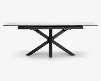 Rektangulært bord med en hvid, marmorlignende bordplade og et moderne sort metalstel. Bordpladen ser ud til at være udtrækkelig med synlige samlinger, der indikerer tillægsplader. Stellet har et geometrisk krydsben-design, som giver stabilitet og et moderne udtryk.