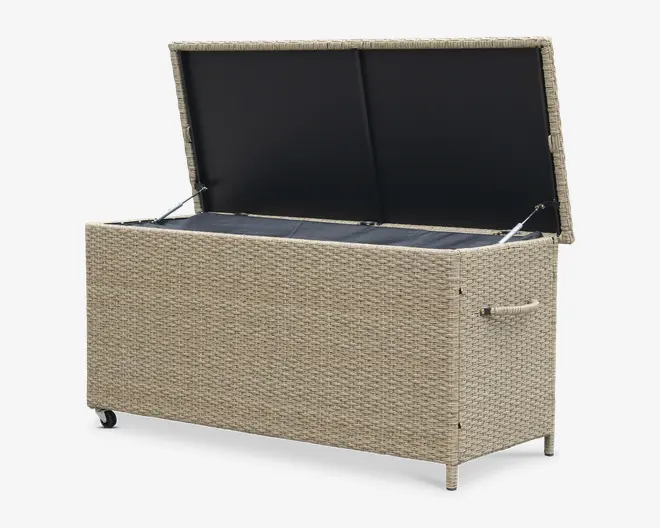 Rektangulær opbevaringsboks med flettet rattan-lignende ydre i en lys beige farve. Boksen har et hængslet låg, der åbnes opad og afslører et rummeligt, foret indre til opbevaring. Den er udstyret med solide sidehåndtag for nem løftning og to små hjul i den ene ende for let mobilitet. Designet er vejrbestandigt og egnet til udendørs brug.