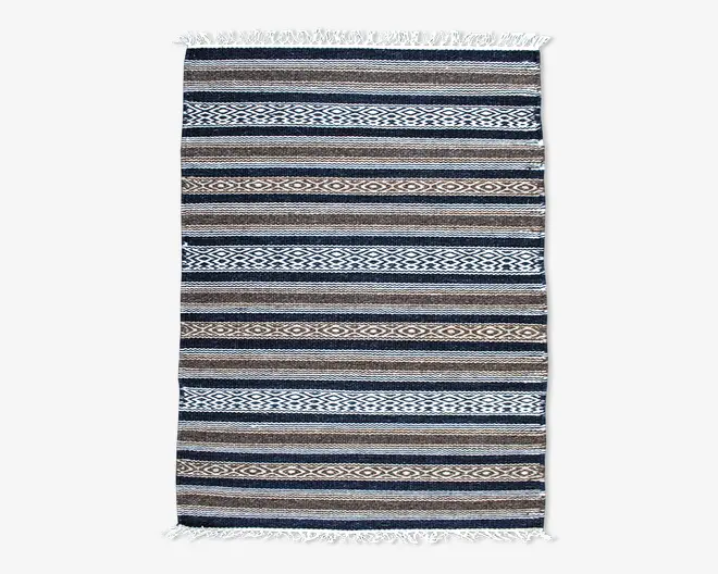 Rektangulært vævet tekstil med horisontale striber i blå, brune, beige og hvide nuancer. Mønstret veksler mellem ensfarvede striber og geometriske diamantmotiver. Begge korte ender har hvide frynser.