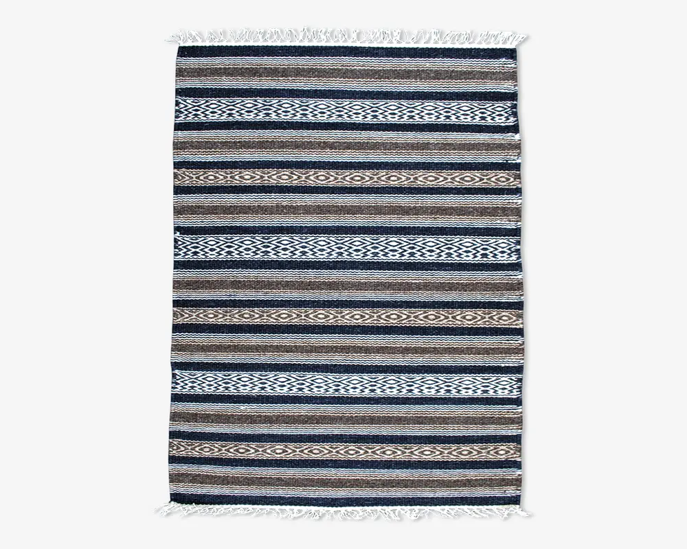 Rektangulært vævet tekstil med horisontale striber i blå, brune, beige og hvide nuancer. Mønstret veksler mellem ensfarvede striber og geometriske diamantmotiver. Begge korte ender har hvide frynser.