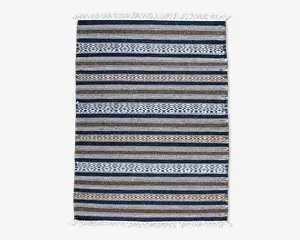 Rektangulært vævet tekstil med horisontale striber i blå, brune, beige og hvide nuancer. Mønstret veksler mellem ensfarvede striber og geometriske diamantmotiver. Begge korte ender har hvide frynser.