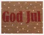 Brun kokosmåtte med teksten 'God Jul' i store, røde bogstaver midt på. Overfladen er dekoreret med jævnt fordelte hvide prikker, der ligner snefnug og giver måtten et julet og festligt udtryk.