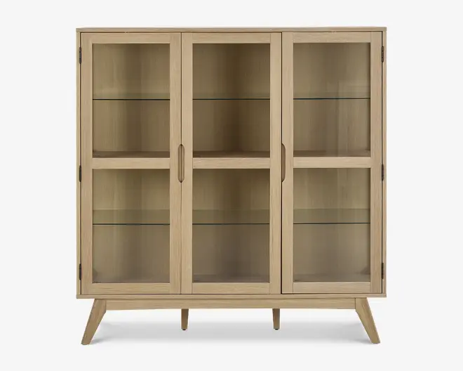 Rektangulært skab med tre glaslåger, lys træramme og skråtstillede ben. Indeholder to indvendige glashylder i hver sektion, hvilket giver god plads til udstilling. Håndtagene er integreret i træet for et stilrent og minimalistisk udtryk.