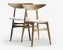 Et par stole i lyst egetræ med buede ryglæn og skråtstillede ben. Sæderne er polstret med glat, hvidt stof, hvilket giver et rent og moderne udtryk. Designet er minimalistisk med bløde, afrundede kanter og en støttende ryg, velegnet til spisebord eller kontor.