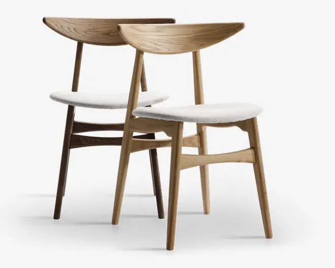 Et par stole i lyst egetræ med buede ryglæn og skråtstillede ben. Sæderne er polstret med glat, hvidt stof, hvilket giver et rent og moderne udtryk. Designet er minimalistisk med bløde, afrundede kanter og en støttende ryg, velegnet til spisebord eller kontor.