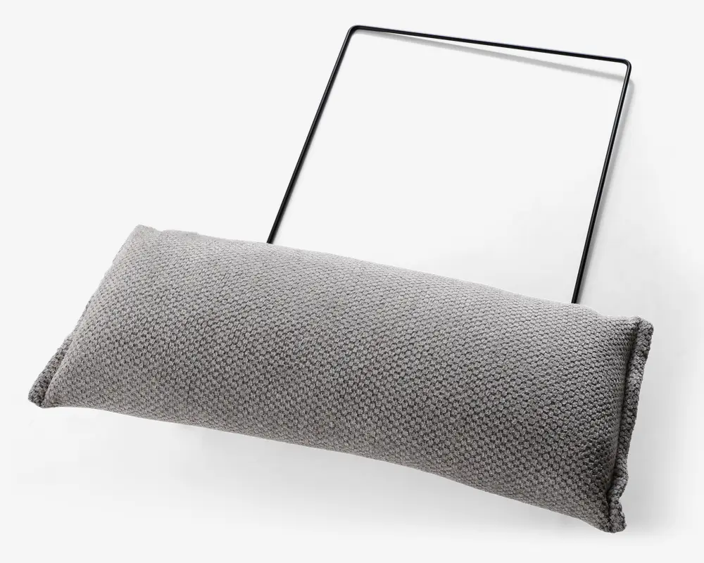 Rektangulær, tekstureret lysegrå pude med et tæt vævet stofbetræk. Puden er fastgjort til en tynd, sort metalramme, som ser ud til at være beregnet til ophængning eller støtte af puden. Pudens kanter er pænt syet, og det samlede design er minimalistisk og moderne.