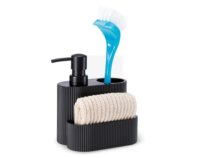 En moderne, sort køkkenorganisator i rillet plast med indbygget sæbepumpe, et rum til en opvaskebørste med blåt håndtag og hvide børster samt en frontlomme med en sammenrullet beige strikket klud. Organisatoren har et stilrent og kompakt design med separate sektioner, der holder rengøringsredskaberne organiseret og let tilgængelige.