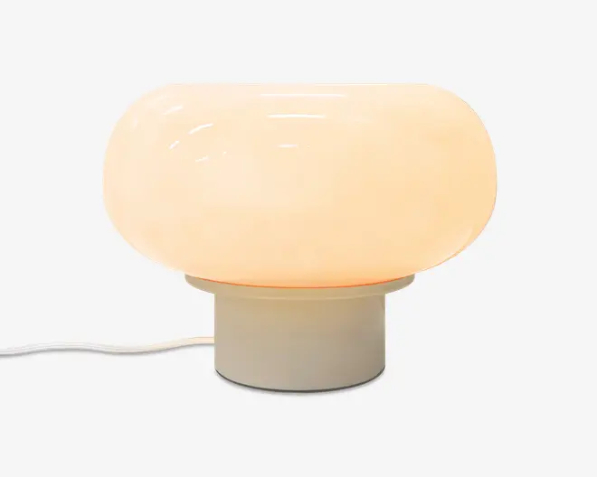 En svampeformet bordlampe med blank, opal cremefarvet skærm, kort cylindrisk base og synlig hvid ledning.