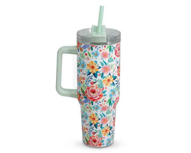 Høj, cylindrisk drikkebæger med stort håndtag og gennemsigtigt låg med et mintgrønt sugerør. Ydersiden er dekoreret med et livligt blomstermønster i nuancer af pink, gul, blå og grøn, hvilket giver et muntert og farverigt udseende.