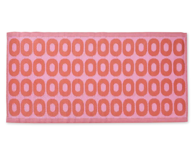 Rektangulært måtte med lyserød baggrund og et gentaget mønster af store, afrundede orange ovaler arrangeret i rækker. Måtten har en tekstureret overflade og en pænt afsluttet kant.