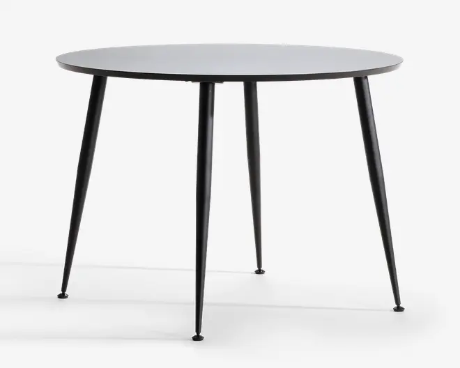 Rundt bord med en glat, flad overflade og fire slanke, tilspidsede metalben. Bordpladen har et minimalistisk design med en tynd profil, og benene er vinklet udad for stabilitet. Finishen er mat, hvilket giver bordet et moderne og stilrent udseende.