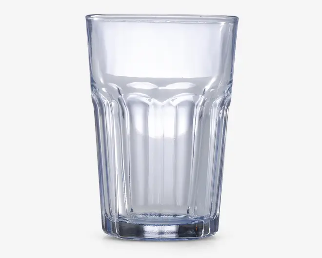 Klar glastumbler med tyk bund og lodrette riller på siderne for bedre greb. Glasset har en let konisk form, bredere foroven og smallere forneden, samt en glat kant for behagelig drikning.