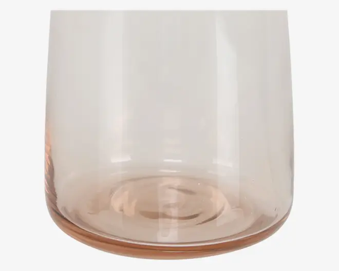 Nærbillede af den nederste halvdel af et transparent glas med et diskret lyserødt skær. Glasset har en glat, afrundet bund og lige sider samt en tyk bund for stabilitet. Overfladen er blank og uden mønstre eller dekorationer.