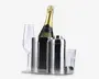 Billedet viser et sæt barudstyr i poleret rustfrit stål, herunder en høj isspand med lodrette riller, en cocktailshaker med tilhørende låg og et klart glas tumbler. Der er også et champagneglas af klart glas. Is-spanden indeholder en flaske champagne med gyldent folie på toppen og sort etiket. Udseendet er moderne og elegant, velegnet til servering af drikkevarer til fest eller sammenkomst.
