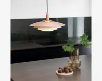 En moderne pendellampe med en lagdelt, skiveformet skærm i en blød rosa farve. Lampen hænger i en sort ledning og udsender et varmt, diffust lys nedad. Designet er minimalistisk og nutidigt, velegnet til køkkener eller spisestuer. Lampens overflade virker mat, og den lagdelte konstruktion reducerer blænding og giver jævn belysning.