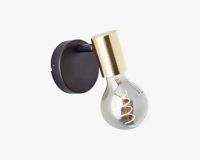 Væghængt lampe med rund sort base og cylindrisk fatning i guld. Den synlige pære har en spiralformet glødetråd, hvilket giver et moderne og industrielt udtryk.