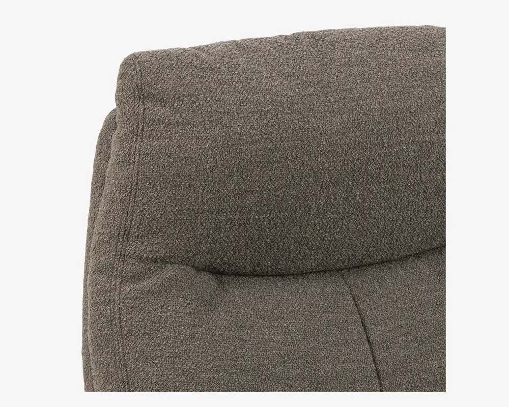 Nærbillede af en polstret overflade med tekstureret, mørkegråt stofbetræk. Stoffet er tæt vævet, og puden har synlige syninger og lette indsyninger, hvilket giver et blødt og støttende udtryk.