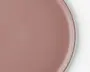 Et nærbillede af en rund tallerken med en glat, mat overflade i en afdæmpet rosa farve. Tallerkenen har en let forhøjet kant og en ensartet overflade, hvilket giver den et moderne og minimalistisk udtryk.