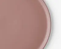Et nærbillede af en rund tallerken med en glat, mat overflade i en afdæmpet rosa farve. Tallerkenen har en let forhøjet kant og en ensartet overflade, hvilket giver den et moderne og minimalistisk udtryk.