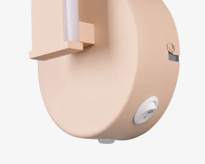Nærbillede af et produkt med en glat, mat beige overflade. Designet har en rundet krop med en tydelig tænd/sluk-knap placeret nederst på siden. Foran er der et lodret element, som kan have en funktionel eller dekorativ rolle. Udtrykket er moderne og minimalistisk.
