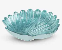 En dekorativ skål lavet af gennemsigtigt turkis glas, formet som et stort blad eller en musling med teksturerede riller og bølgede kanter. Overfladen har en blank finish, og designet har fine detaljer, der efterligner naturlige mønstre, hvilket giver et elegant og kunstnerisk udtryk.