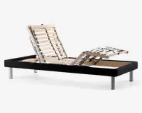 Justerbar sengebund med sort stoframme og sølvfarvede metalben. De lamellerede træsektioner er opdelt i tre zoner, så hoved-, ryg- og benområderne kan hæves eller sænkes individuelt for optimal komfort. Lamellerne er forstærket med sorte støttebånd for ekstra holdbarhed.