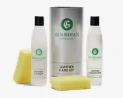 Billedet viser et sæt bestående af to hvide flasker med sorte låg mærket 'Leather Cleaner' og 'Leather Conditioner' fra Guardian Furniture Care. Sættet indeholder også en stor sølvfarvet cylinderformet beholder med teksten 'Leather Care Kit' samt to gule svampe. Flaskerne har et enkelt, moderne design med grøn branding og tekst. Svampene er rektangulære og ser ud til at være lavet af blødt skum, velegnet til påføring af produkterne.