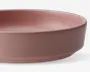 En rund, lav skål med en glat, mat overflade i en afdæmpet rosa farve. Skålen har tykke sider og en flad bund, hvilket giver et robust og moderne udtryk. Både indersiden og ydersiden er ensfarvet, og kanten er let afrundet for et behageligt greb.