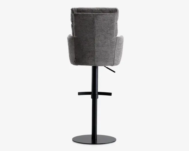 Billedet viser en stol med høj, polstret ryg og armlæn, betrukket med et gråt tekstil med struktur. Stolen har en solid sort metalbase med rund fod og et håndtag til højdejustering. Bagsiden af stolen har synlige lodrette syninger.